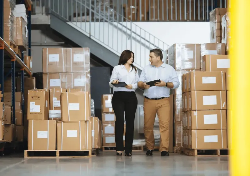 two people talking in a warehouse surrounded by boxes